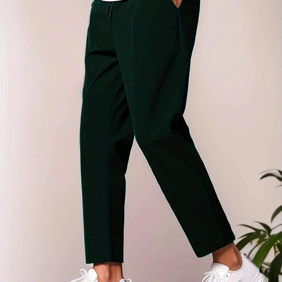 Close-up of black casual pants paired with white sneakers on a light background