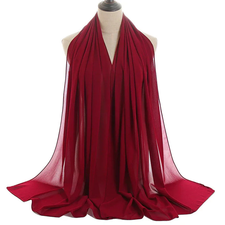 Elegant deep red chiffon scarf draped on beige mannequin with flowing fabric folds
