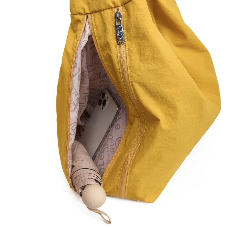 Yellow zippered bag open showing smartphone and folded beige umbrella inside