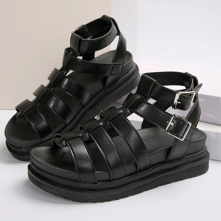 Black leather gladiator sandals with ankle buckles and cushioned sole on white background