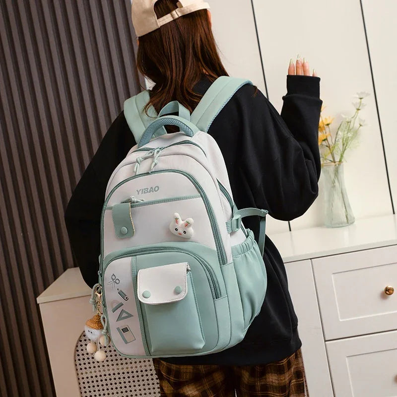 Woman wearing a stylish white and mint green YIBAO backpack with multiple compartments indoors