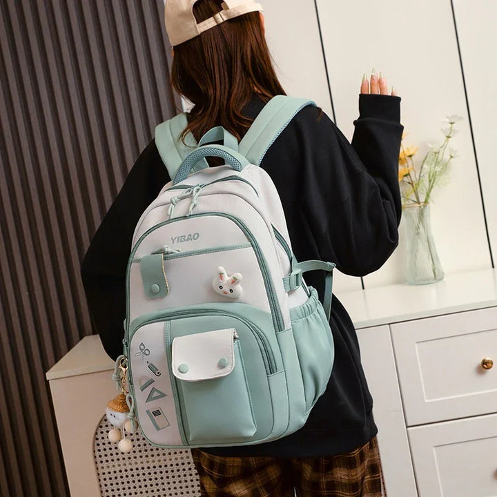 Woman wearing a stylish white and mint green YIBAO backpack with multiple compartments indoors