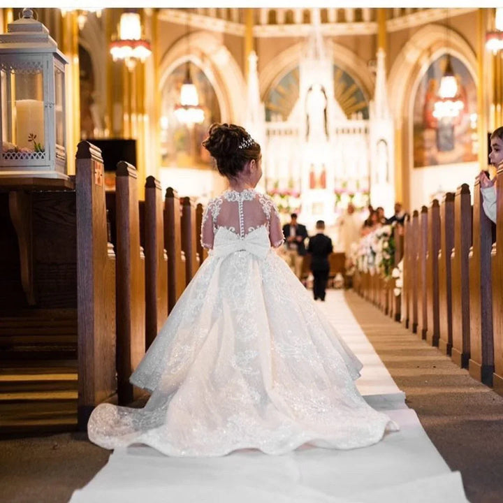 Little girl in white lace dress walking down church aisle during wedding ceremony