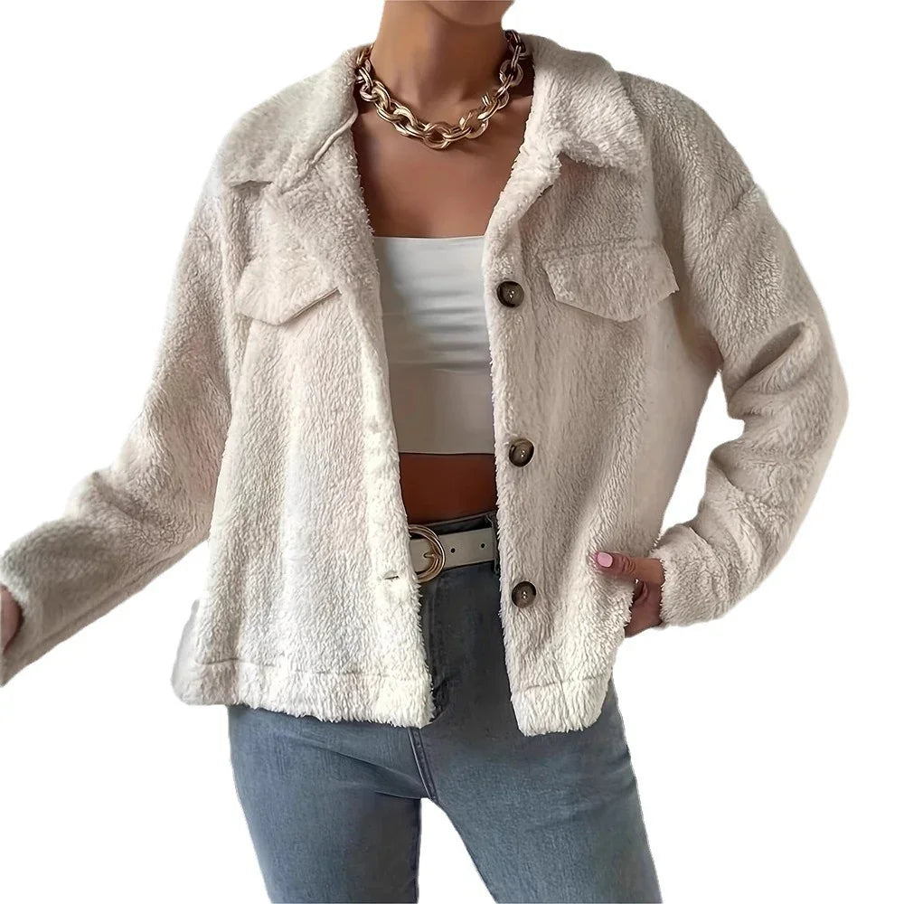 Woman wearing cream sherpa fleece jacket with buttons, white crop top, blue jeans, and gold chain necklace