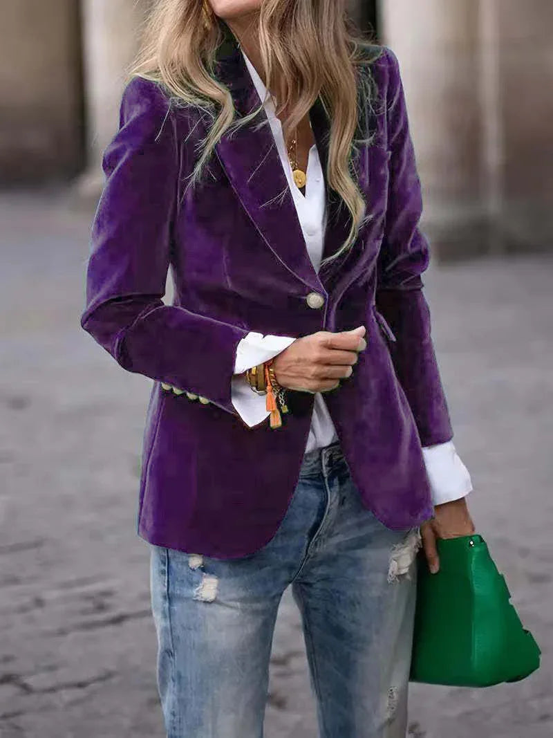 Woman wearing purple velvet blazer with white shirt and ripped blue jeans holding green handbag