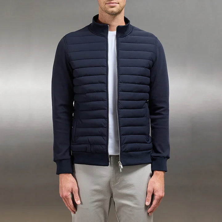 Man wearing navy blue quilted padded jacket with zip front and ribbed cuffs over white shirt