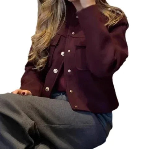 Woman wearing a dark burgundy buttoned jacket and gray pants with loose curls hairstyle