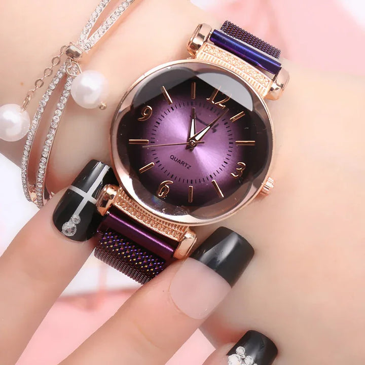 Close-up of purple watch with rose gold case and mesh strap on wrist with black and rhinestone nail art