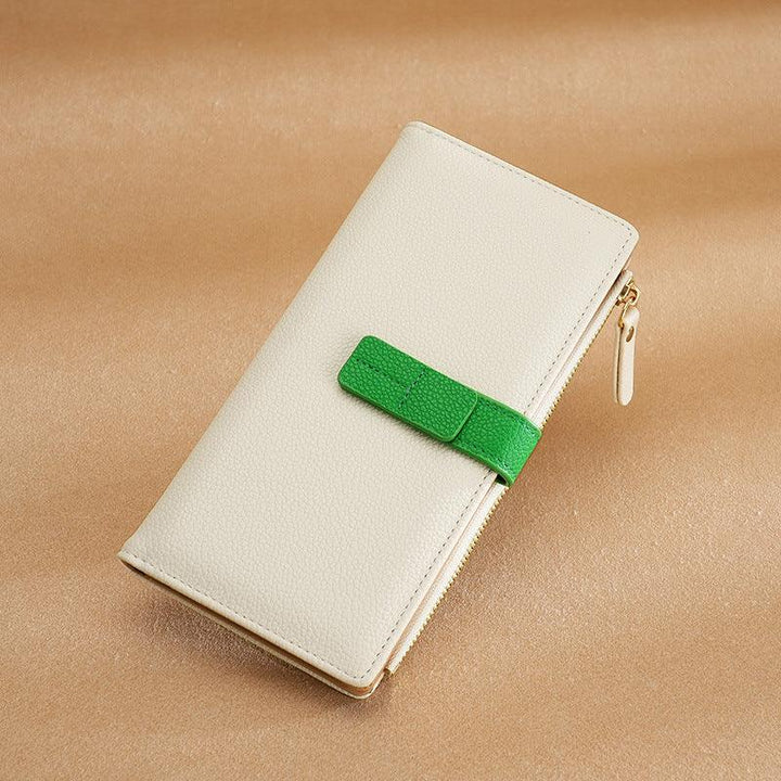 Beige leather wallet with green strap and gold zipper on tan textured surface