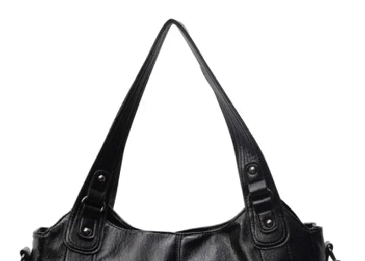Black leather shoulder handbag with double straps and metal studs on a white background