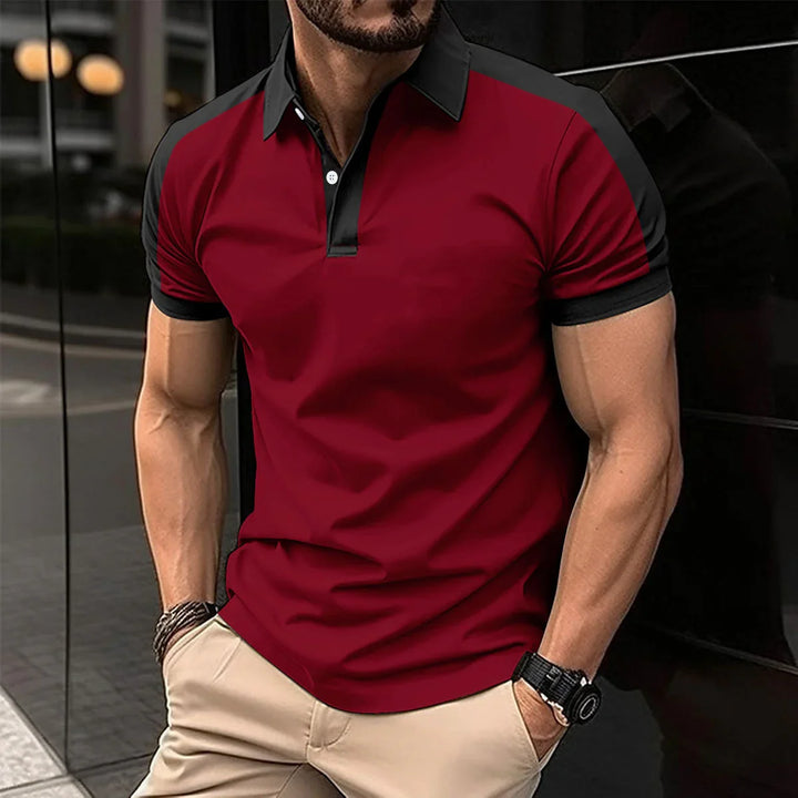 muscular man wearing red and black short-sleeve polo shirt with beige pants standing outdoors