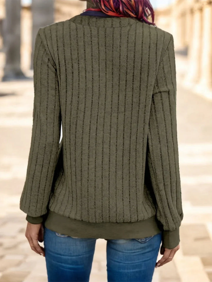 Back view of woman wearing green ribbed knit sweater with balloon sleeves and blue jeans outdoors