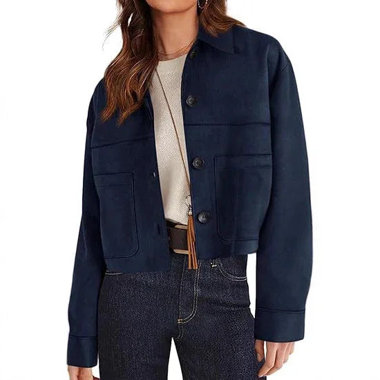 Woman wearing navy blue button-up cropped jacket with front pockets over white top and dark jeans