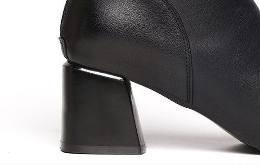 Close-up of black leather ankle boot with chunky block heel on white background