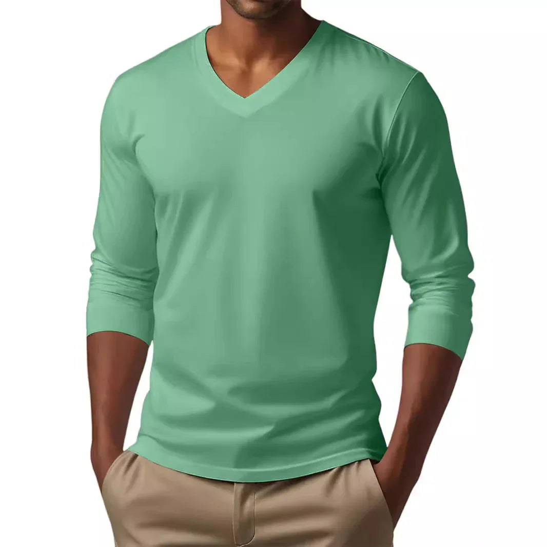 Man wearing a mint green V-neck long sleeve shirt with beige pants, hands in pockets