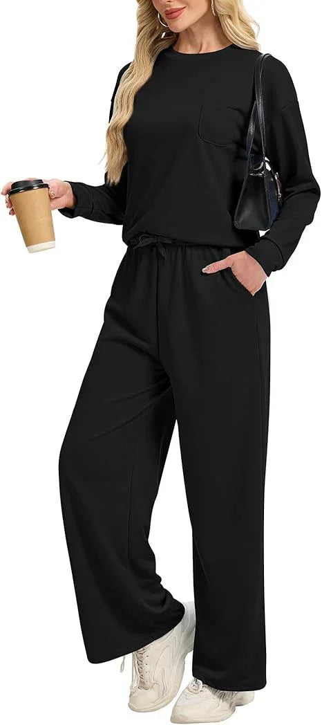 woman wearing black long-sleeve top and wide-leg pants holding coffee cup and black handbag