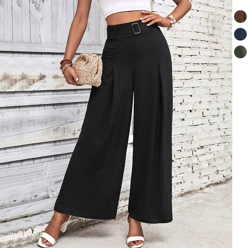 Woman wearing high-waisted black wide-leg pants with belt, white crop top, white heels, and holding woven clutch