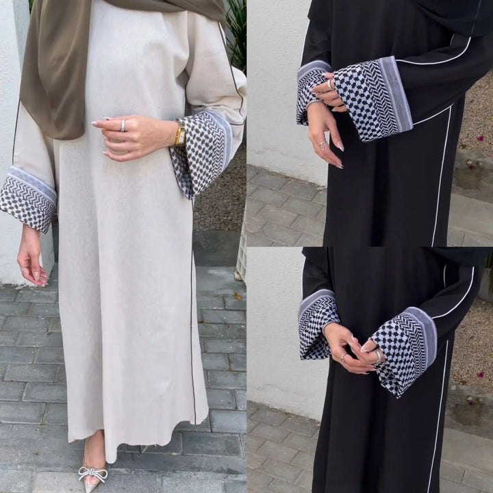 Two women's abayas with patterned cuffs, one beige with brown hijab, one black, worn outdoors on paved ground