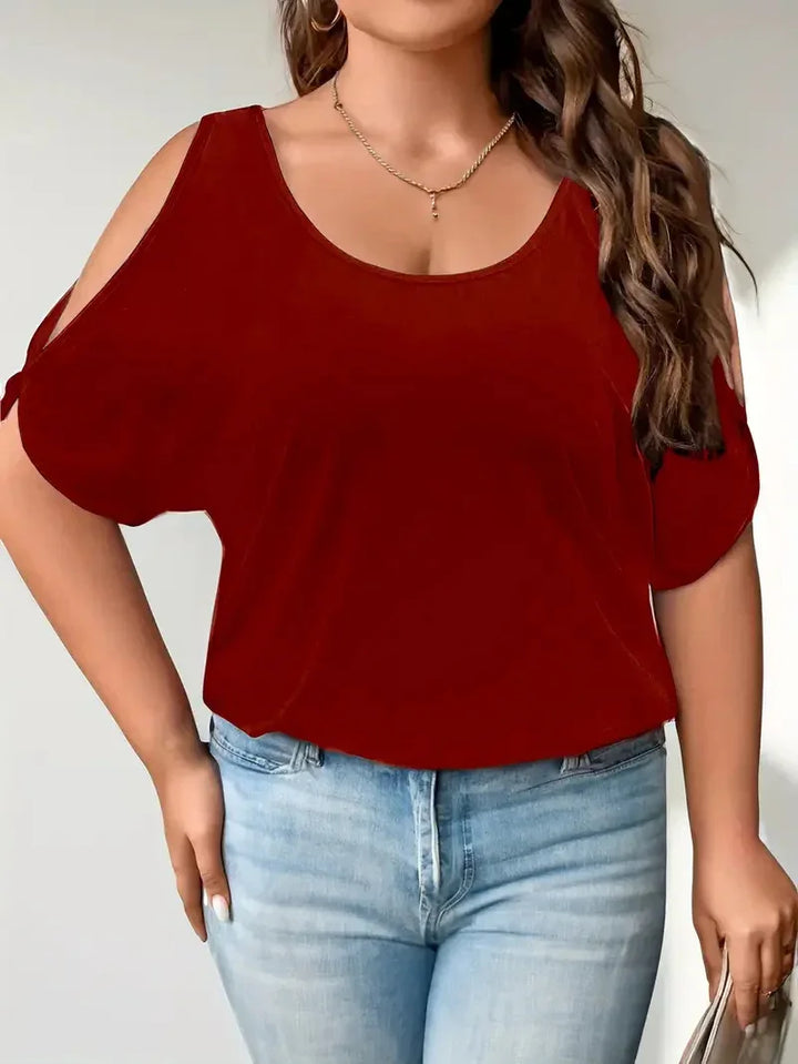 Woman wearing burgundy cold shoulder top with short sleeves and light blue jeans