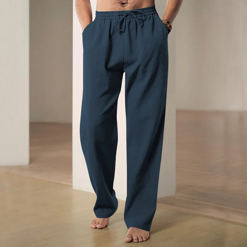 Man wearing navy blue relaxed fit lounge pants with drawstring in minimal indoor setting