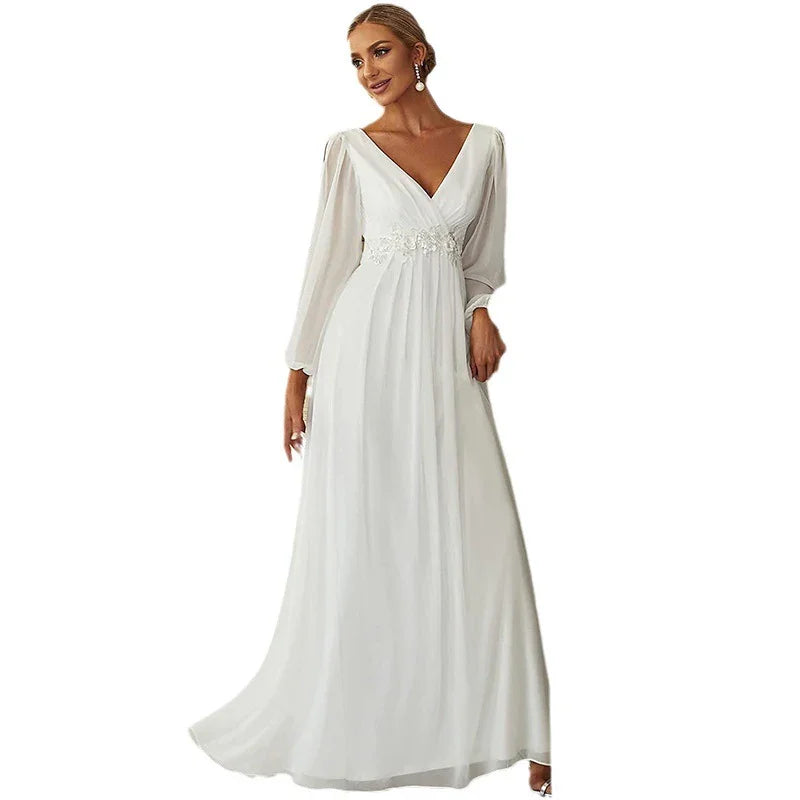 Elegant woman wearing long white V-neck evening gown with sheer sleeves and floral waistband