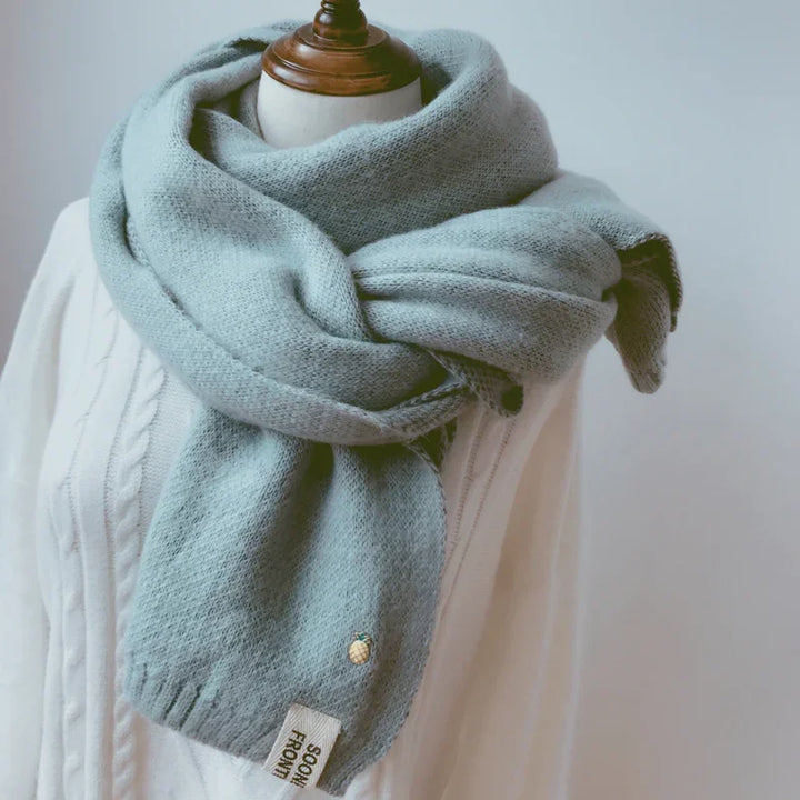 Light blue cozy knit scarf wrapped on mannequin wearing white cable knit sweater