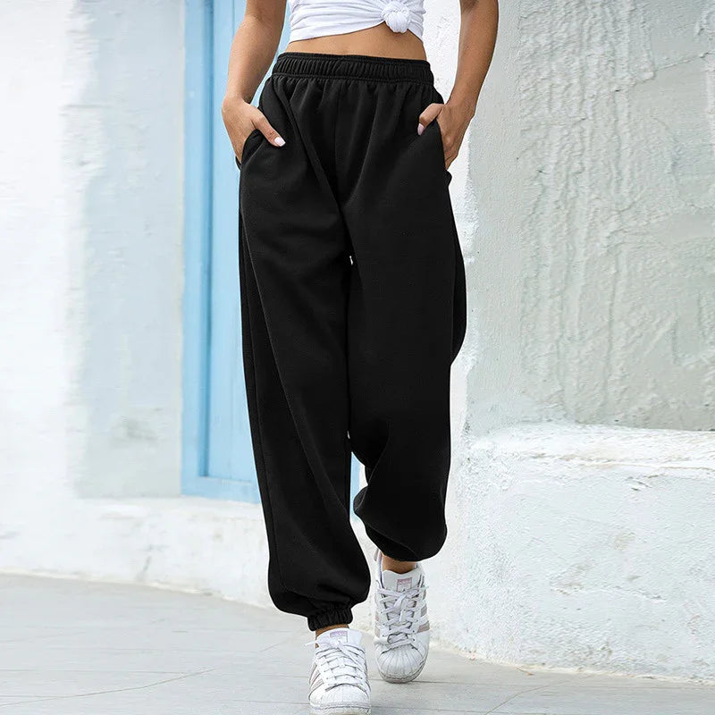Woman wearing black high-waisted jogger pants and white sneakers walking outdoors