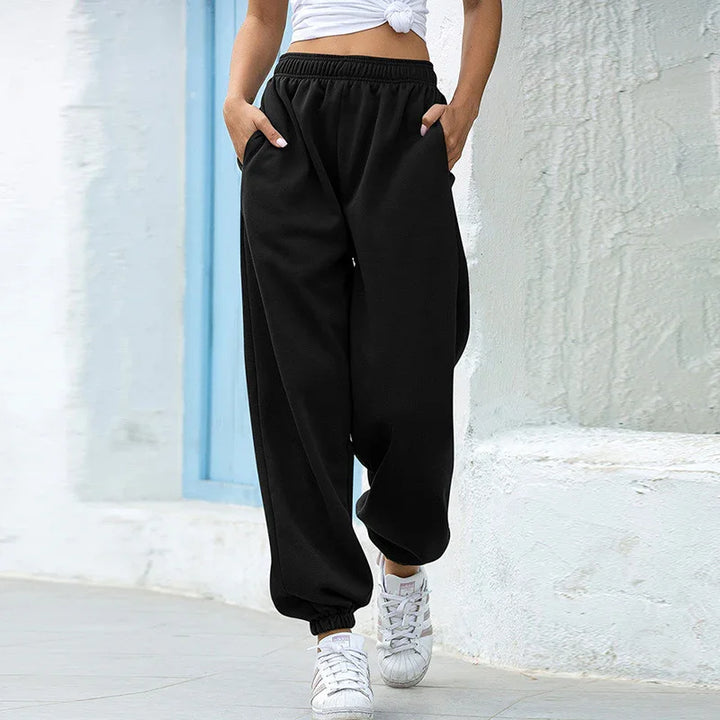Woman wearing black high-waisted jogger pants and white sneakers walking outdoors