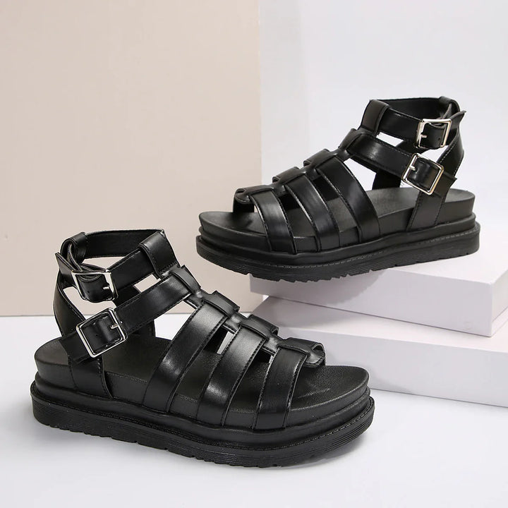 Black leather gladiator sandals with double silver buckles and thick sole on white display