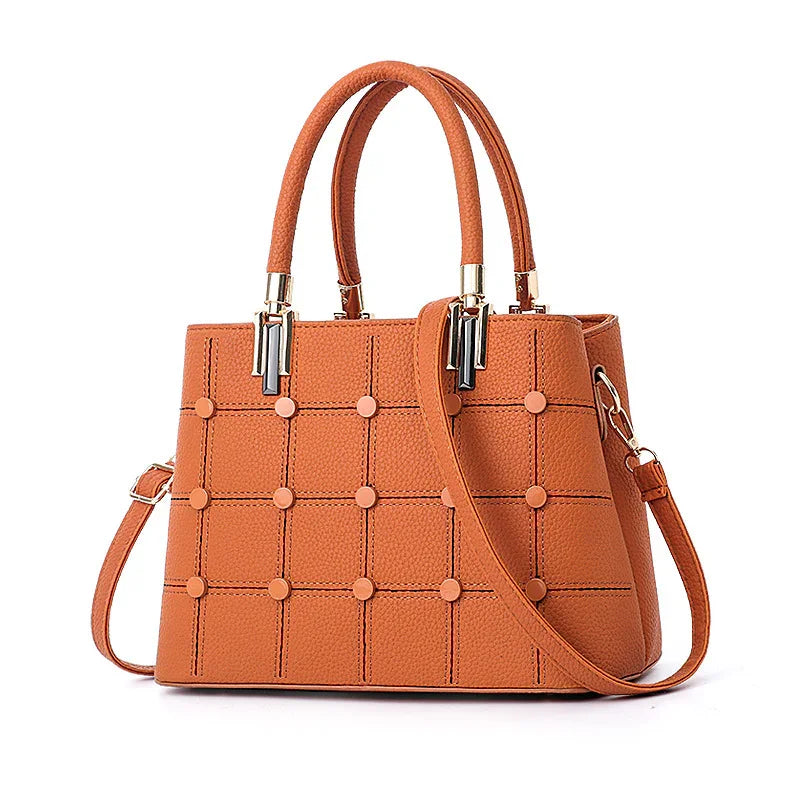 Orange textured leather handbag with grid pattern and round studs, dual handles and detachable strap