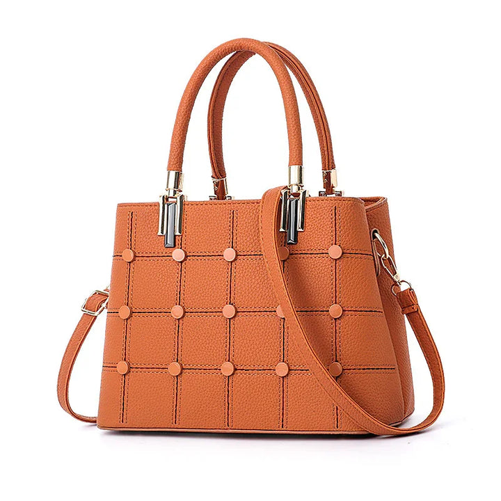 Orange textured leather handbag with grid pattern and round studs, dual handles and detachable strap