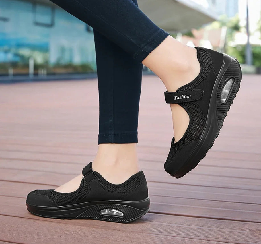 Black casual Mary Jane sneakers with air-cushioned sole worn with dark skinny jeans on wooden deck