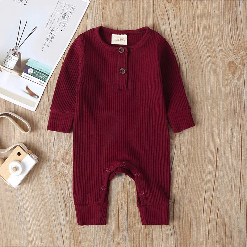 Maroon ribbed long-sleeve baby romper with buttons on front and snap closures at legs on wooden floor