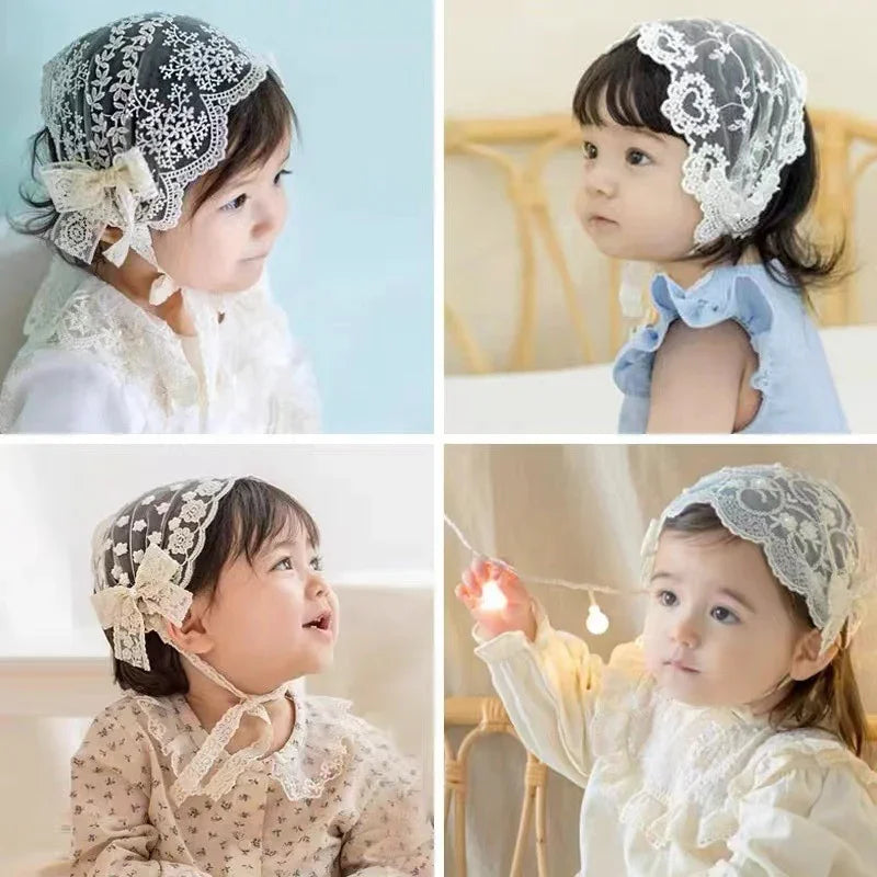 Four babies wearing delicate lace bonnets and vintage-inspired outfits in soft, natural light