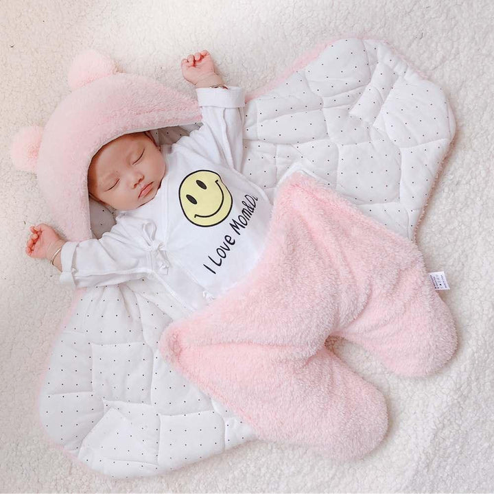 Sleeping baby in a pink bear hoodie and white onesie with smiley face and I Love Mom text on soft blanket