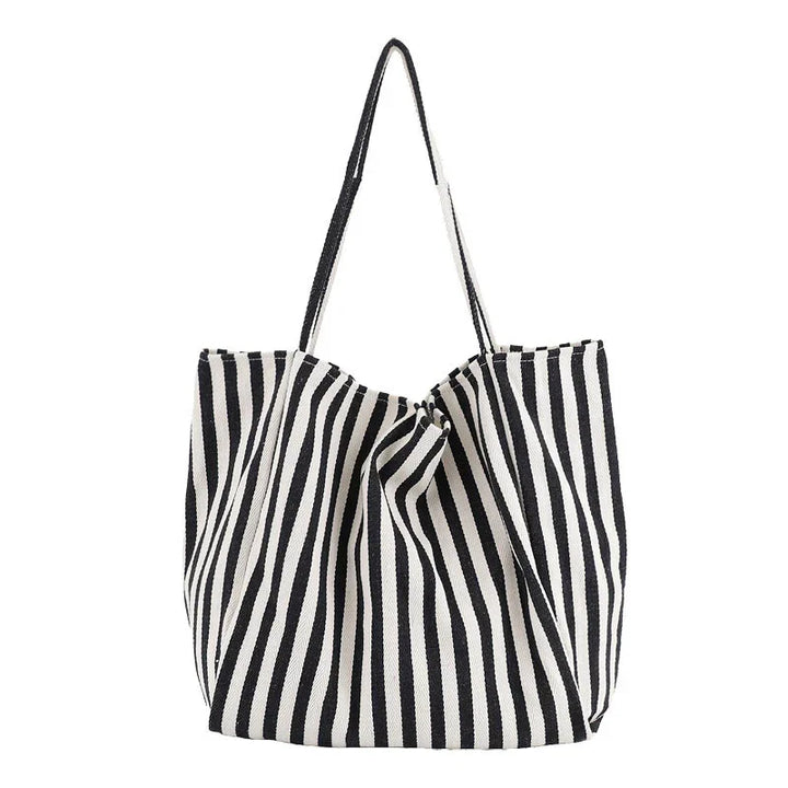 Black and white vertical striped tote bag with long handles on white background