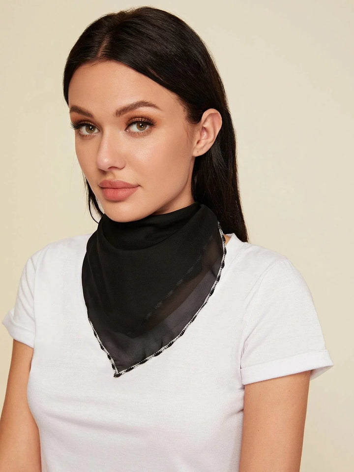 Woman wearing black sheer scarf with delicate white trim over white t-shirt against beige background