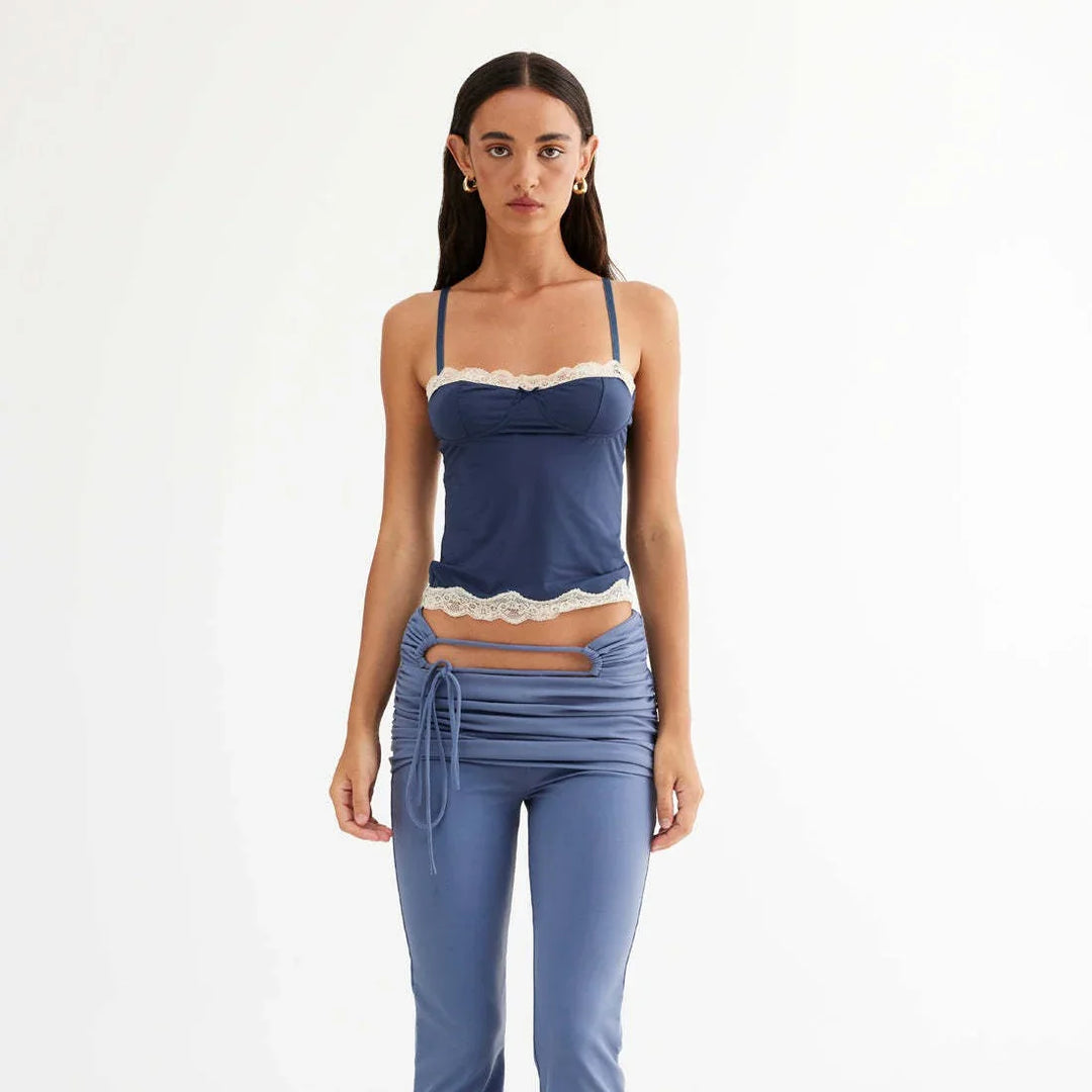 Model wearing blue camisole with white lace trim and matching ruched pants with cutout detail