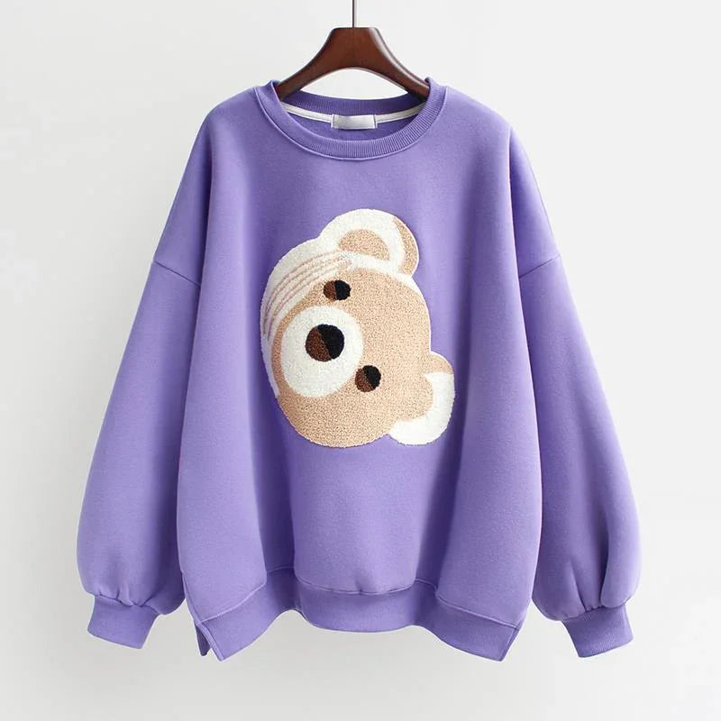 Purple oversized sweatshirt with a textured teddy bear face design on the front