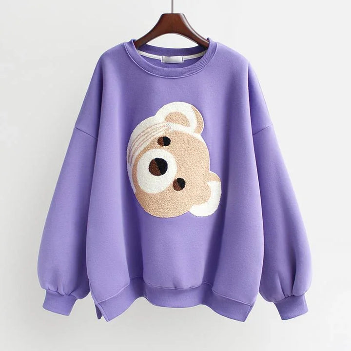 Purple oversized sweatshirt with a textured teddy bear face design on the front