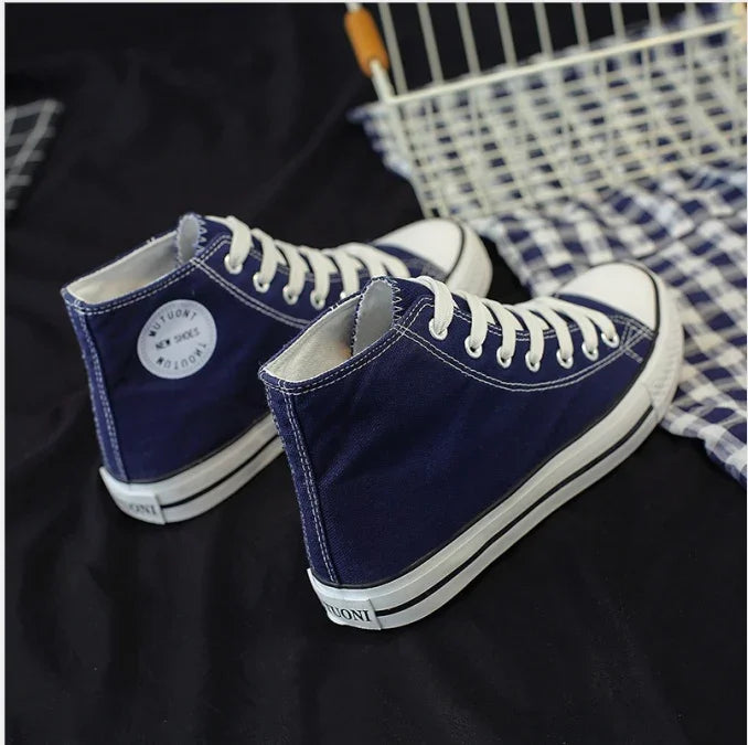 Navy blue high-top canvas sneakers with white laces and rubber soles on black fabric background