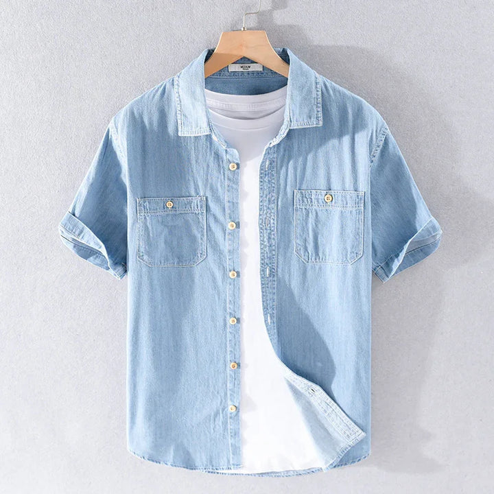 Light blue denim short sleeve shirt layered over white t-shirt on hanger against gray background