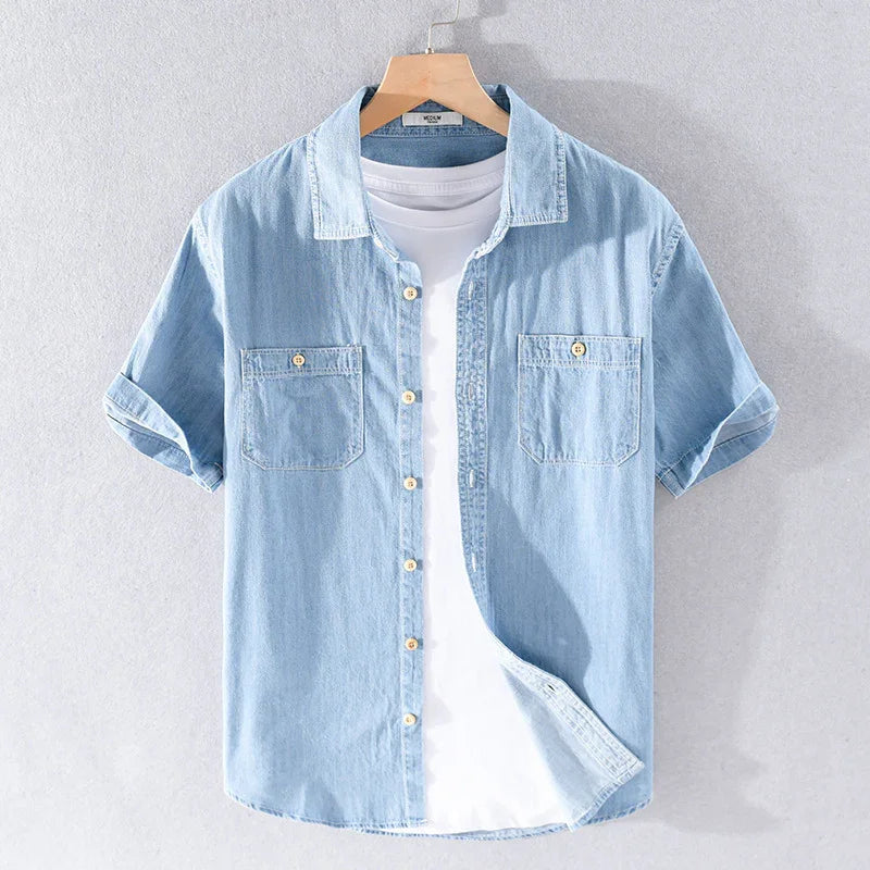 Light blue denim short-sleeve shirt with two chest pockets layered over a white t-shirt on a hanger