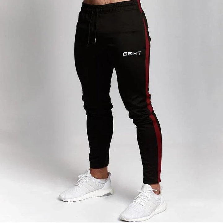Black jogger pants with red side stripes and white branding, paired with white athletic sneakers