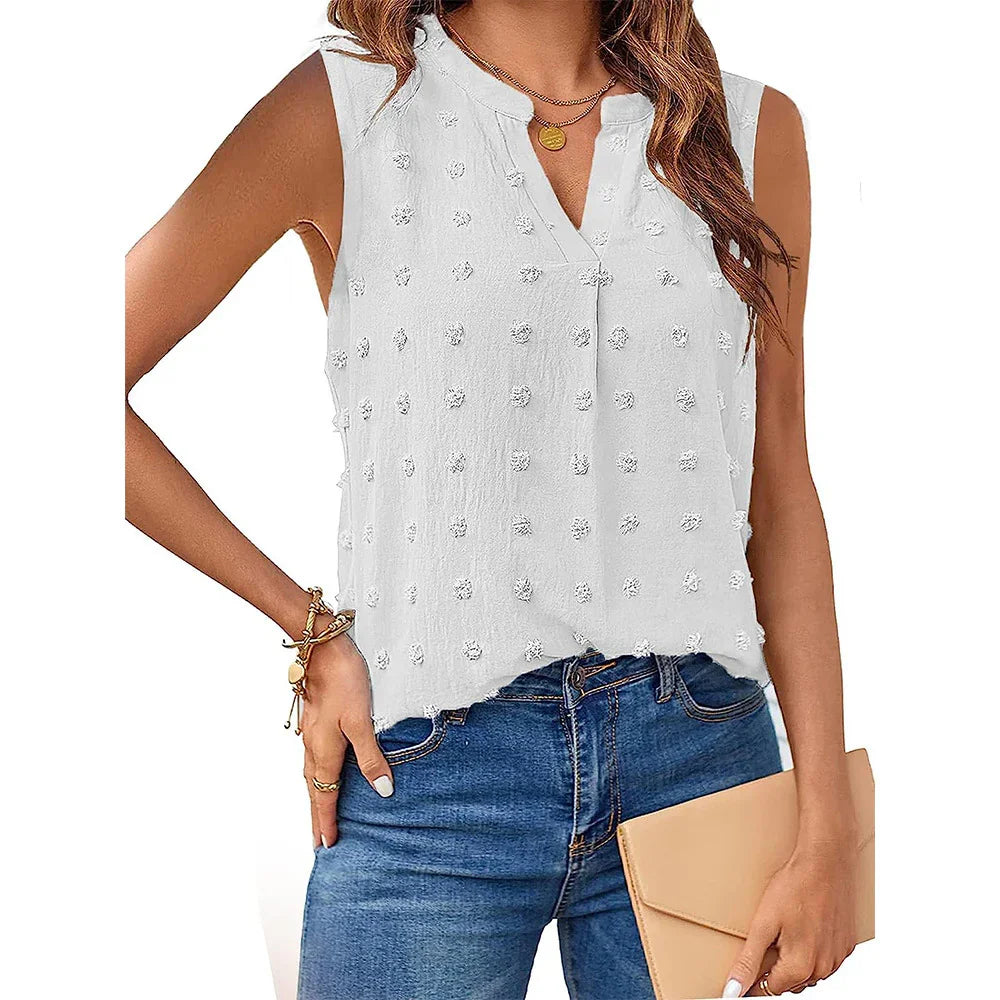 Woman wearing sleeveless white textured blouse with V-neck and blue jeans holding beige clutch