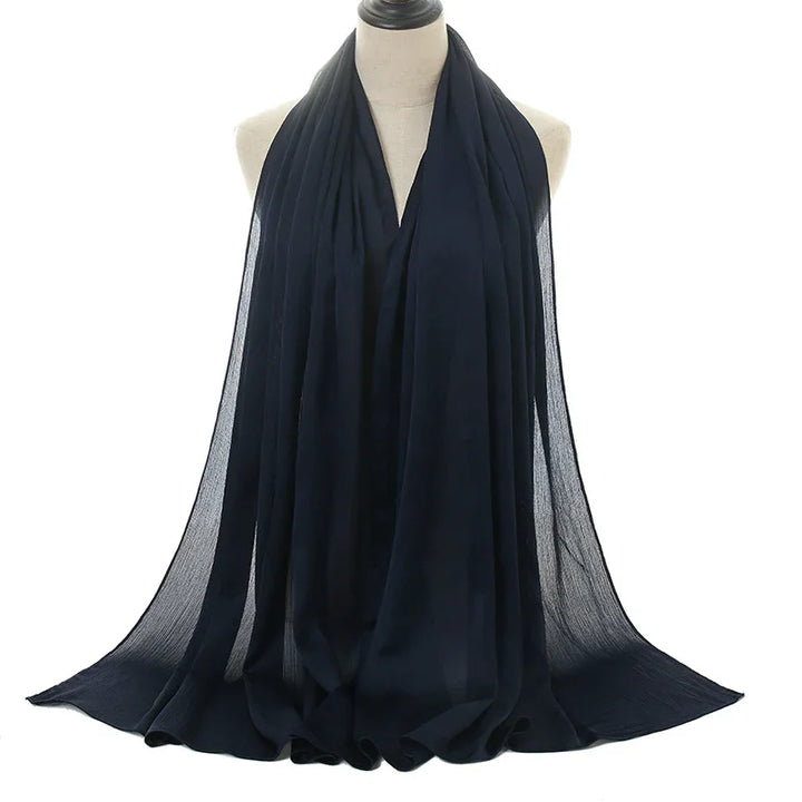 Black lightweight chiffon scarf displayed on a beige dress form against white background