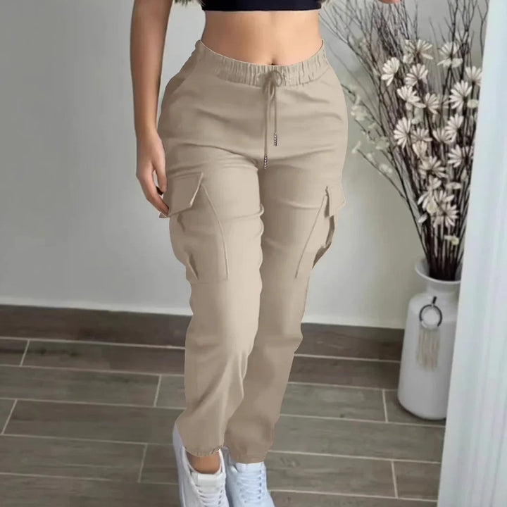 Woman wearing beige cargo pants with drawstring waist and white sneakers on tiled floor