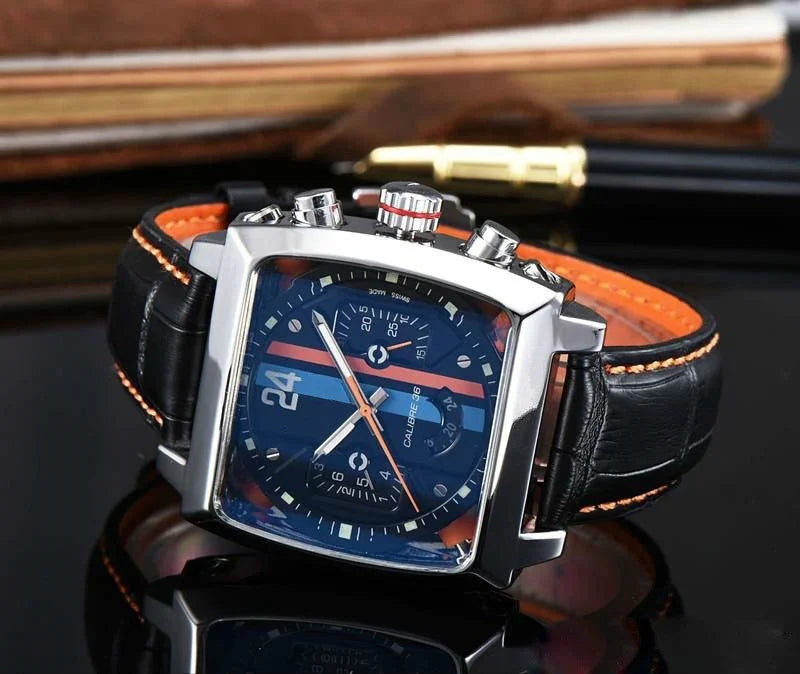 Square chronograph wristwatch with blue dial, black leather strap, orange accents, and silver case