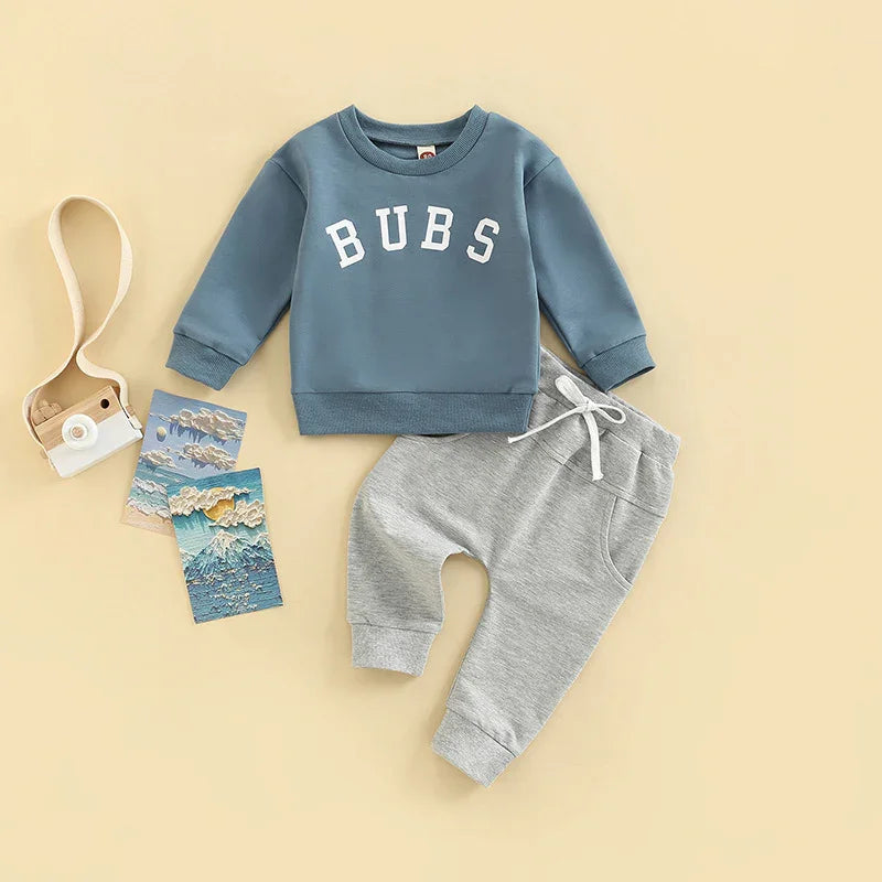 Blue toddler sweatshirt with BUBS text and grey drawstring sweatpants on beige background
