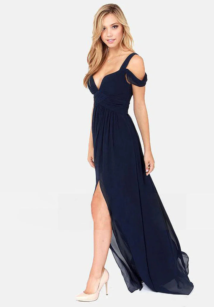 Blonde woman wearing a navy blue off-shoulder evening gown with a thigh-high slit and white heels